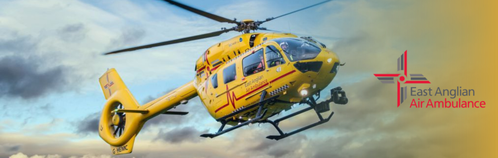 Yellow air ambulance next to the East Anglian Air Ambulance logo.